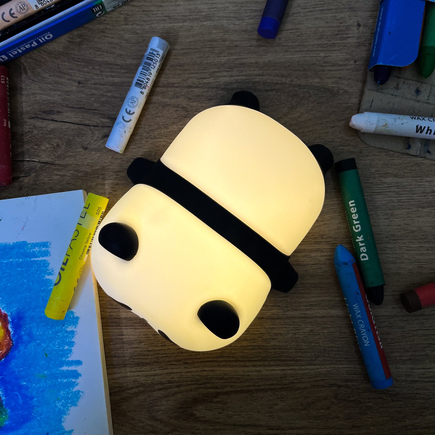 Panda-shaped night light on a wooden surface with markers around